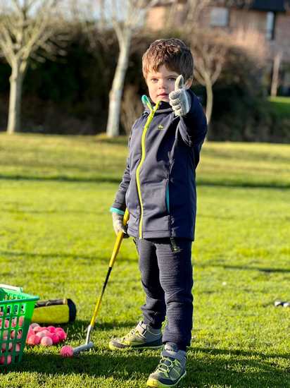 jeune enfants qui lève le pouce, heureux de jouer au golf et d'apprendre